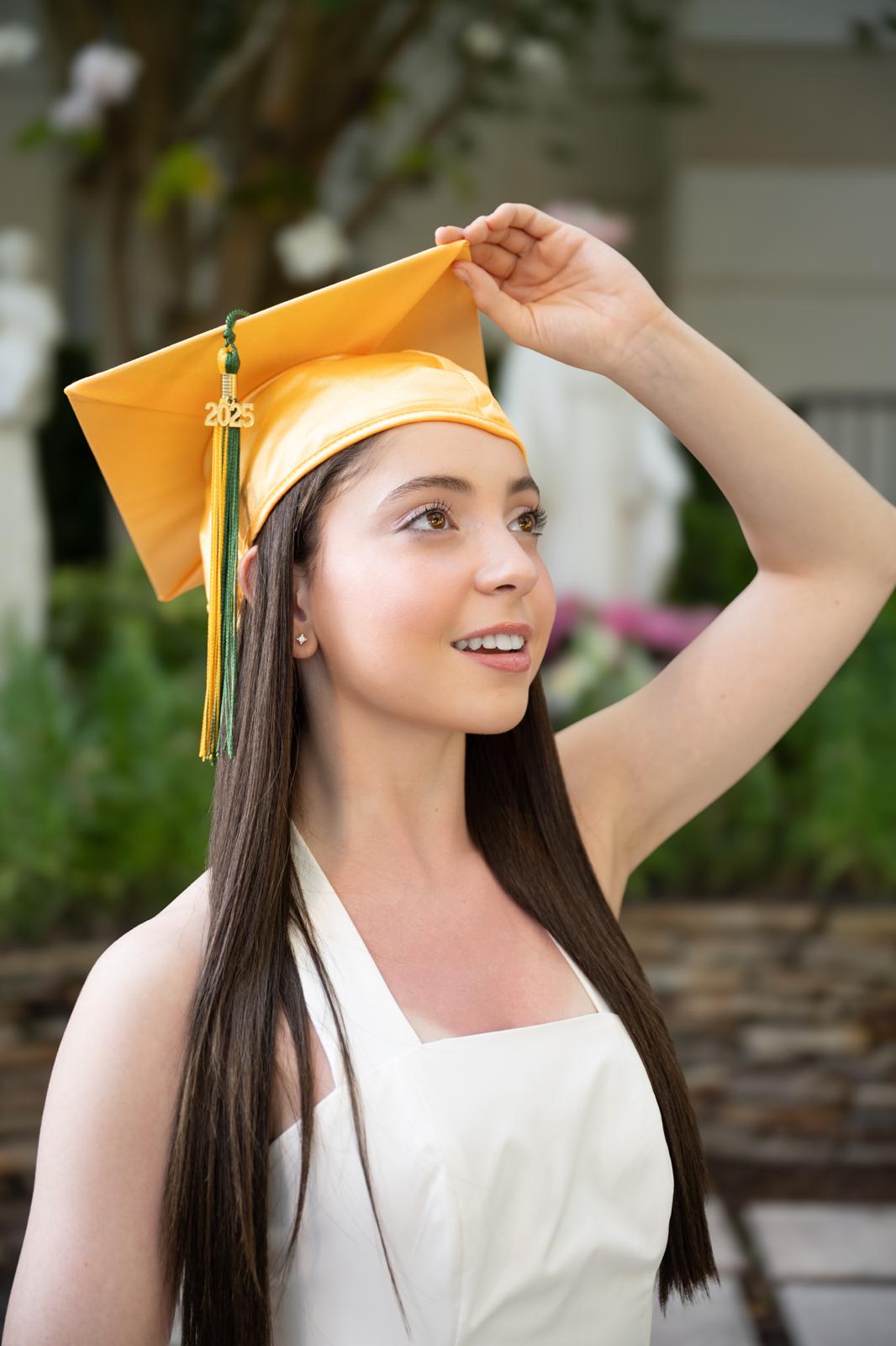 Graduate in a gold 2025 cap adjusting her mortarboard