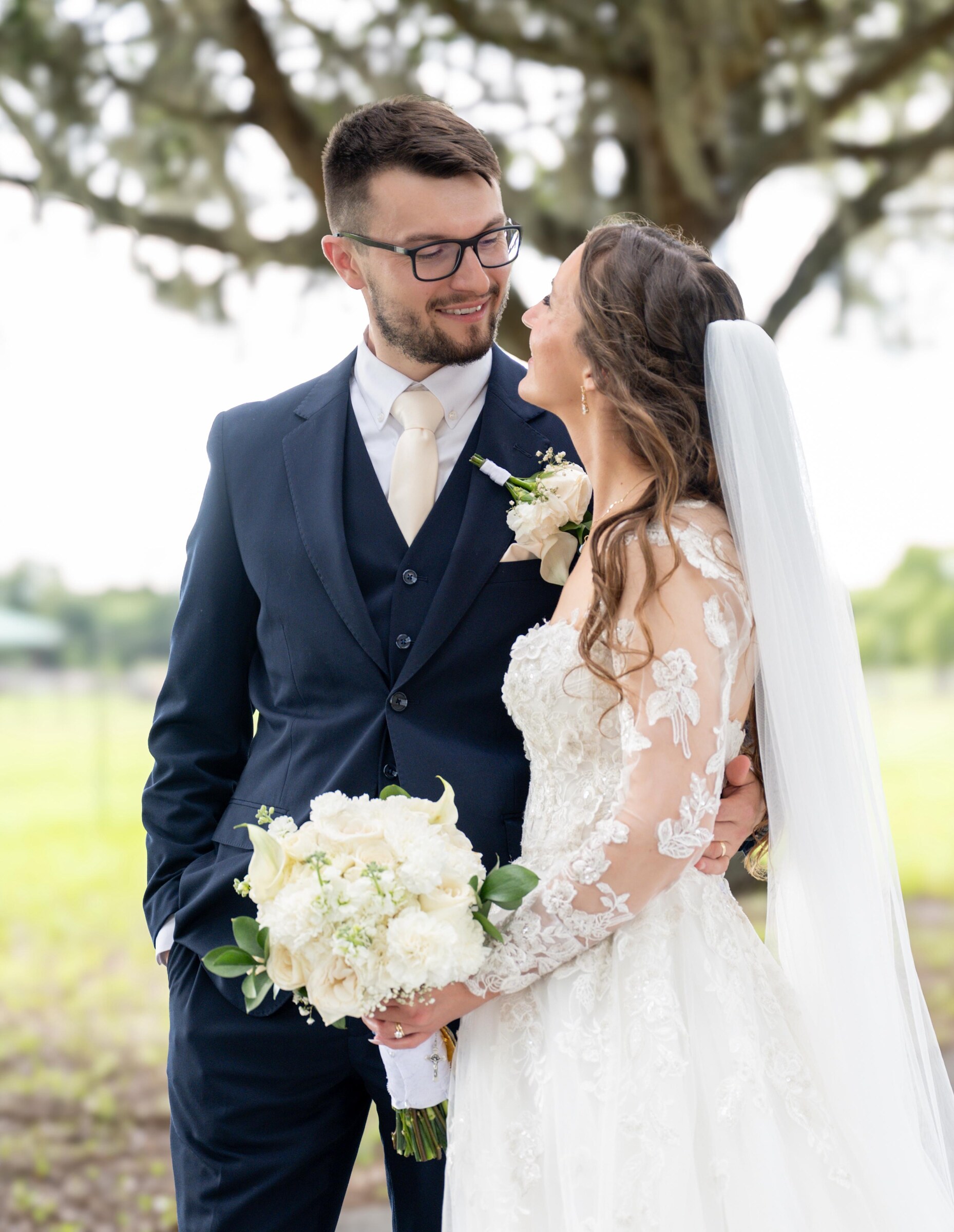 Newlyweds sharing a quiet look beneath an oak tree